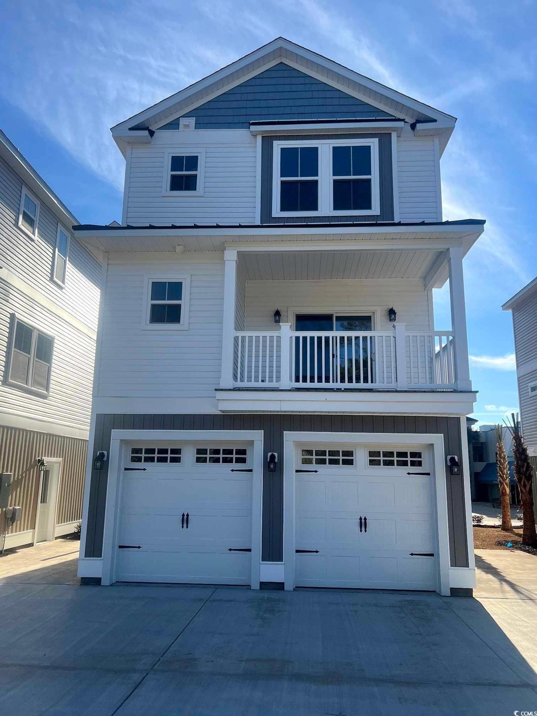 Coastal home with driveway, an attached garage, and a balcony