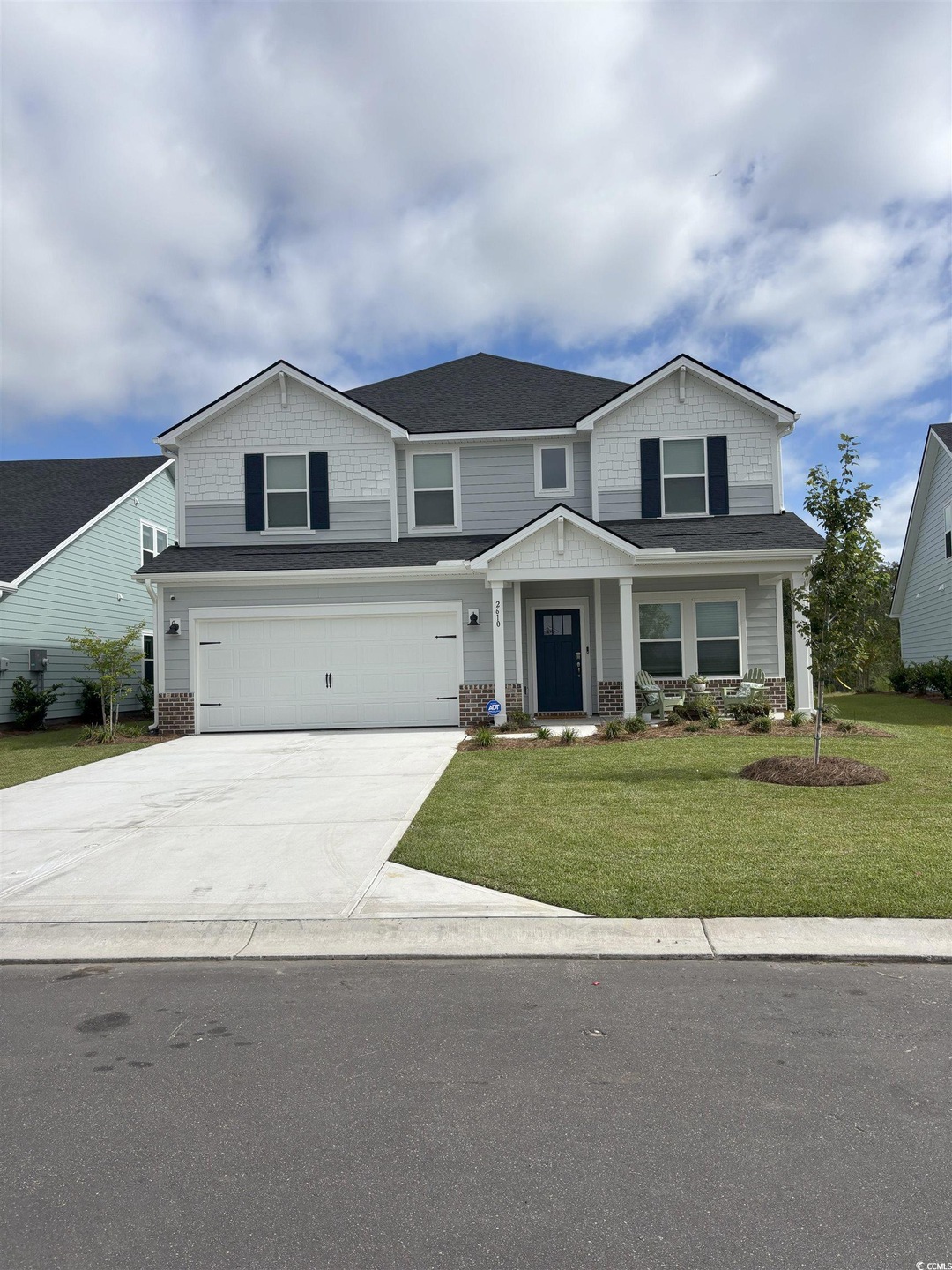 View of front facade with covered porch, concrete driveway, an attached garage, a front yard, and a shingled roof