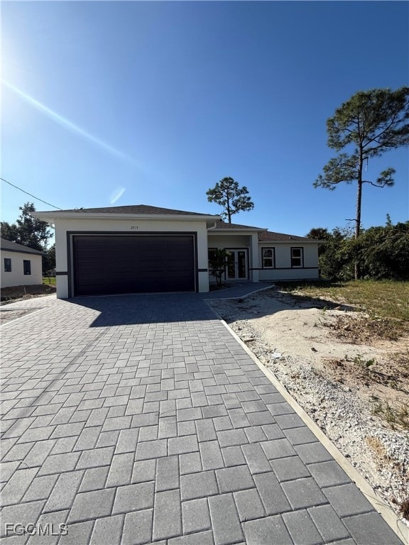 Ranch-style home featuring decorative driveway, a garage, and stucco siding
