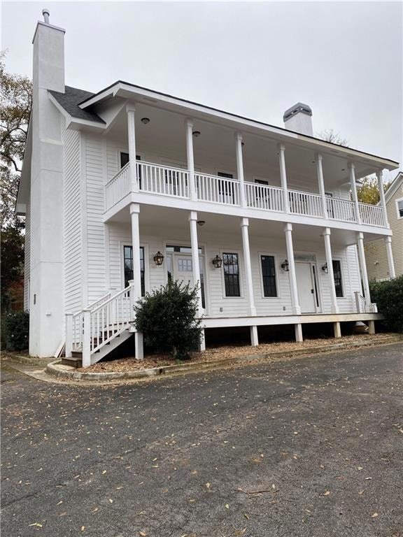 View of front of home featuring a balcony and a chimney