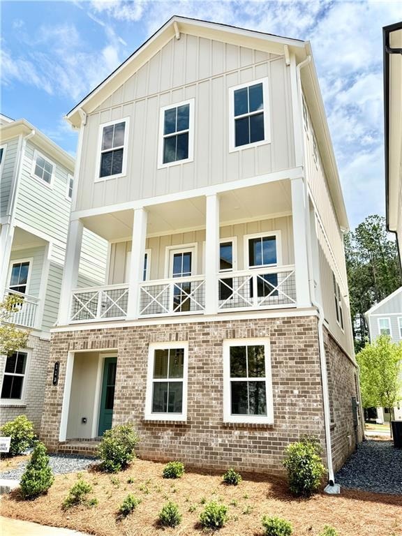 View of front of property featuring board and batten siding, brick siding, and a balcony
