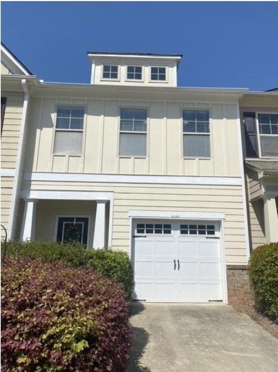 View of front of house with an attached garage, concrete driveway, and board and batten siding