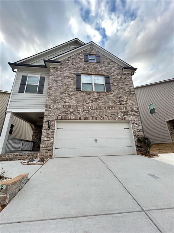 View of front of home with a garage, driveway, and brick siding