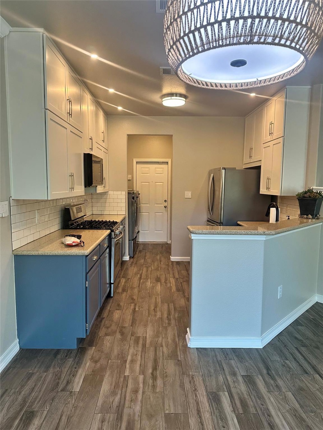 Kitchen with light stone counters, dark wood fini