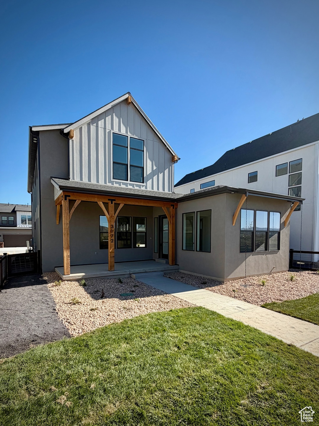 Front door with a lawn, board and batten siding, and a patio