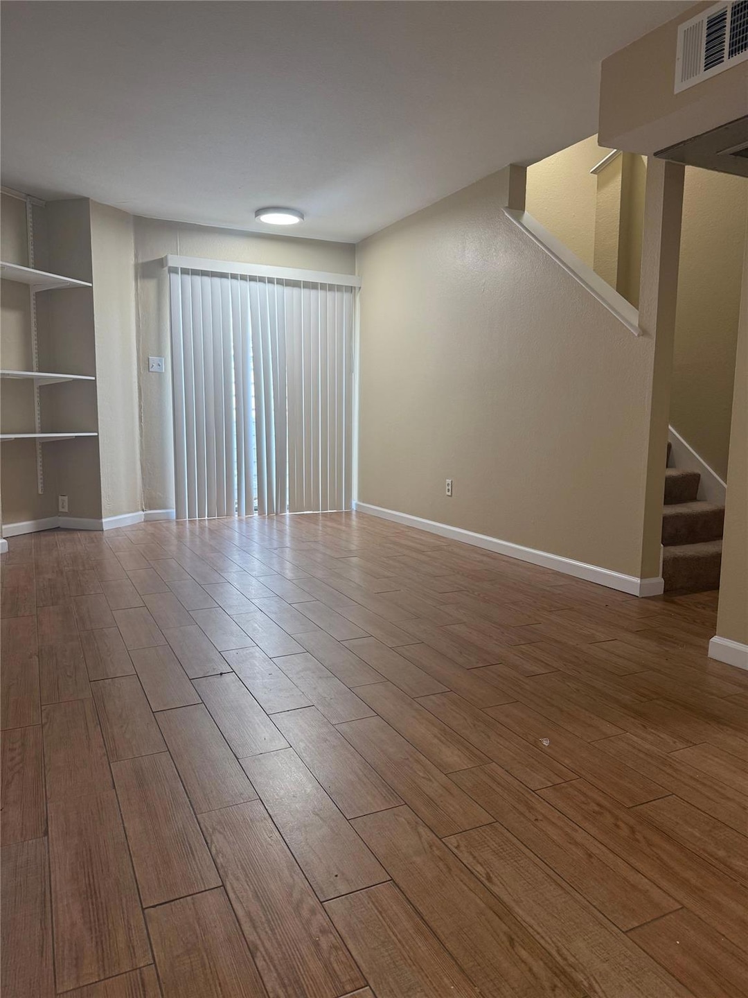 Unfurnished room featuring wood finished floors and stairway