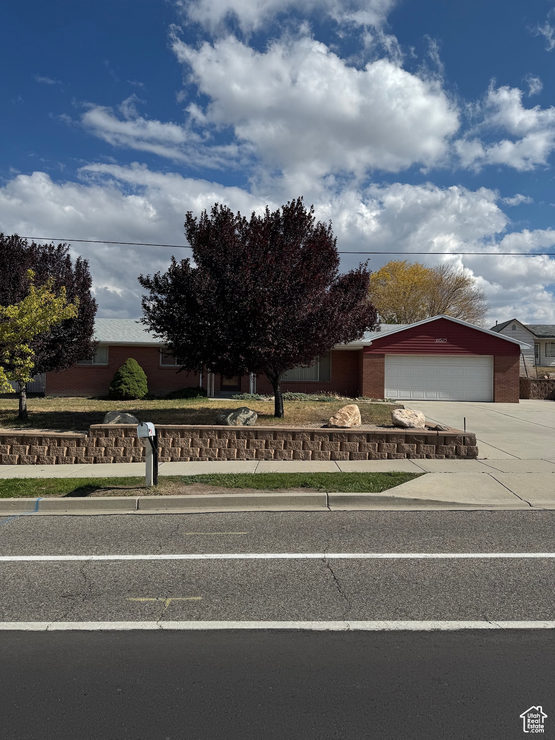 View of front facade featuring a garage, concrete driveway, and brick siding