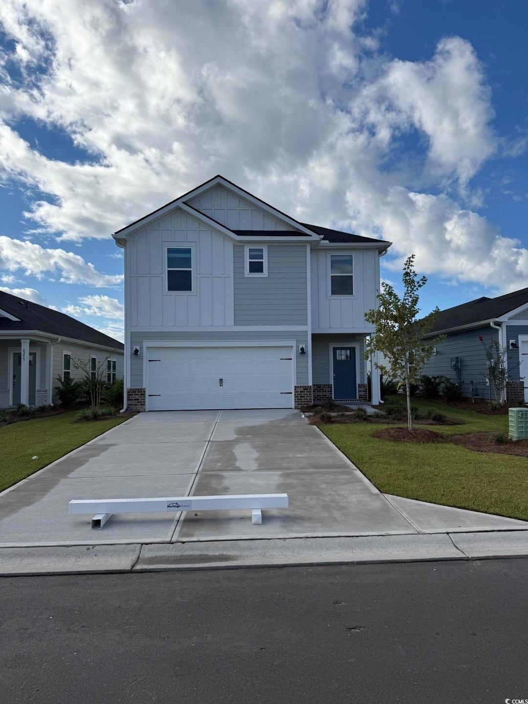 View of front of property with board and batten siding, driveway, an attached garage, and a front yard
