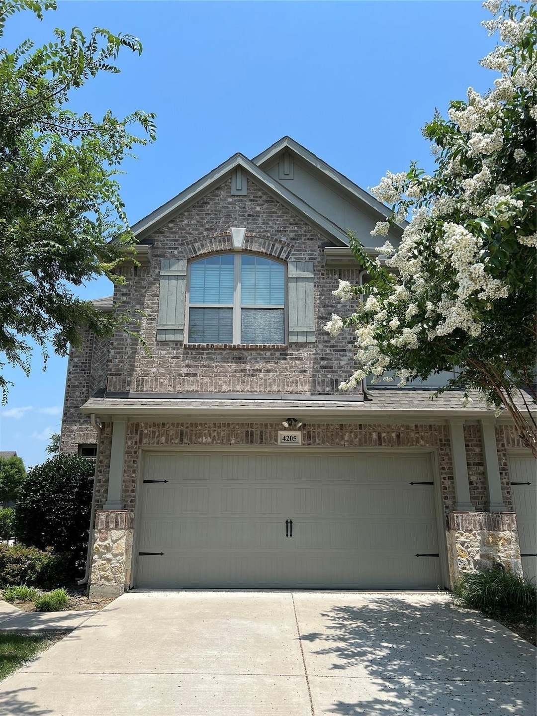 View of front of house featuring brick siding, an attached garage, and driveway