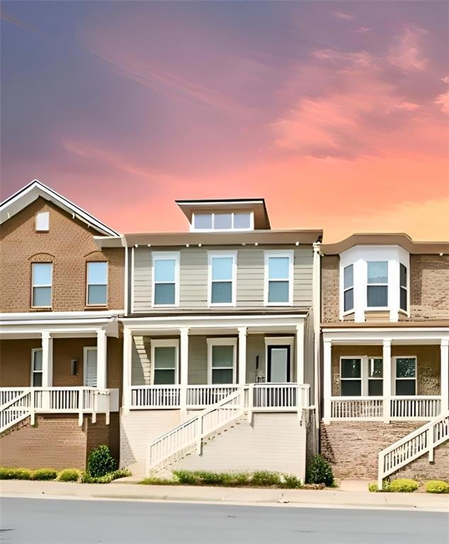 Townhome / multi-family property with stairway and a porch