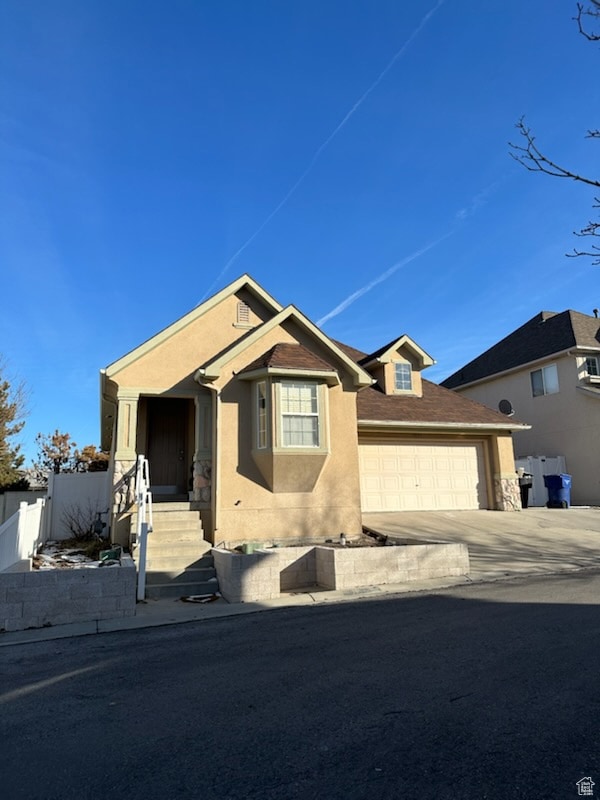 View of front of home featuring concrete driveway, stucco siding, and a garage