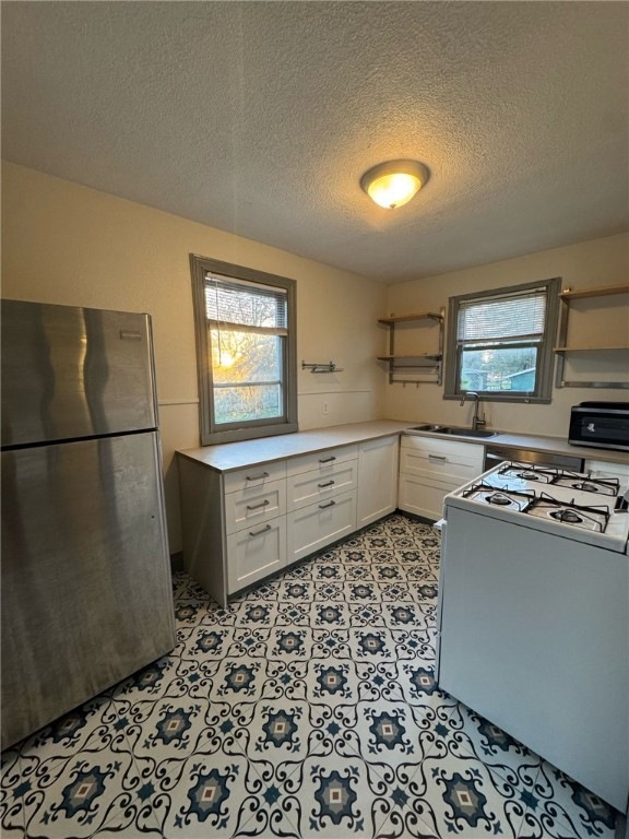 Kitchen with sink, white cabinetry, a textured cei