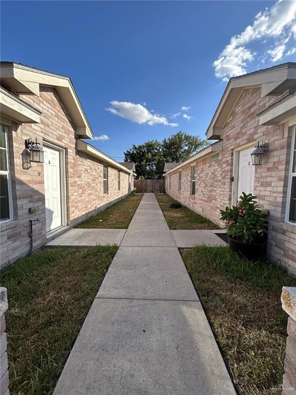 View of property exterior featuring fence and brick siding