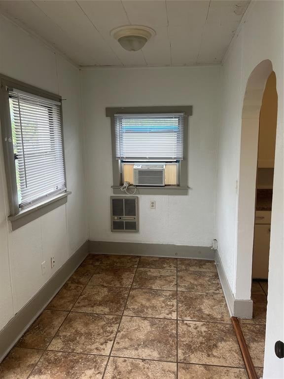 Empty room featuring arched walkways, baseboards, 