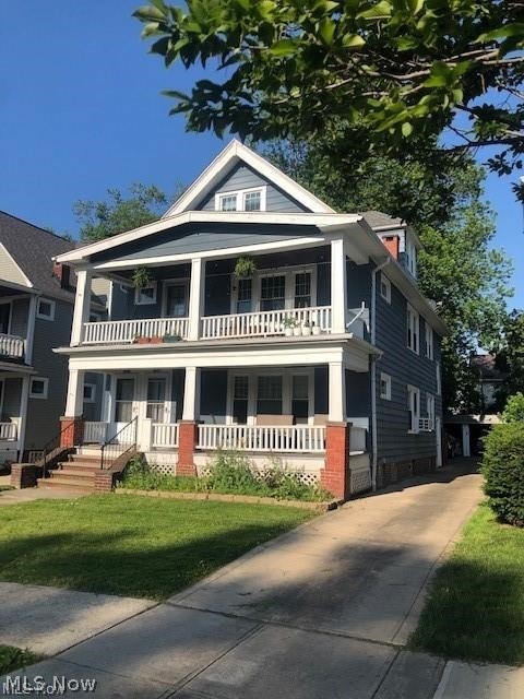 View of front of home with a front yard and a balcony