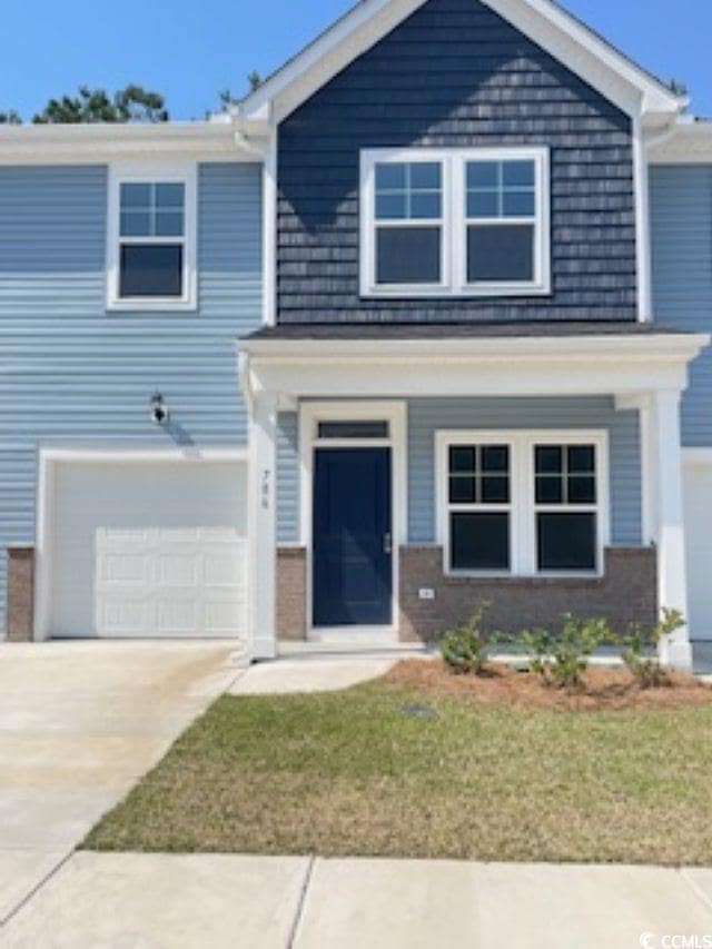 View of front of house featuring a garage, driveway, a front yard, and brick siding