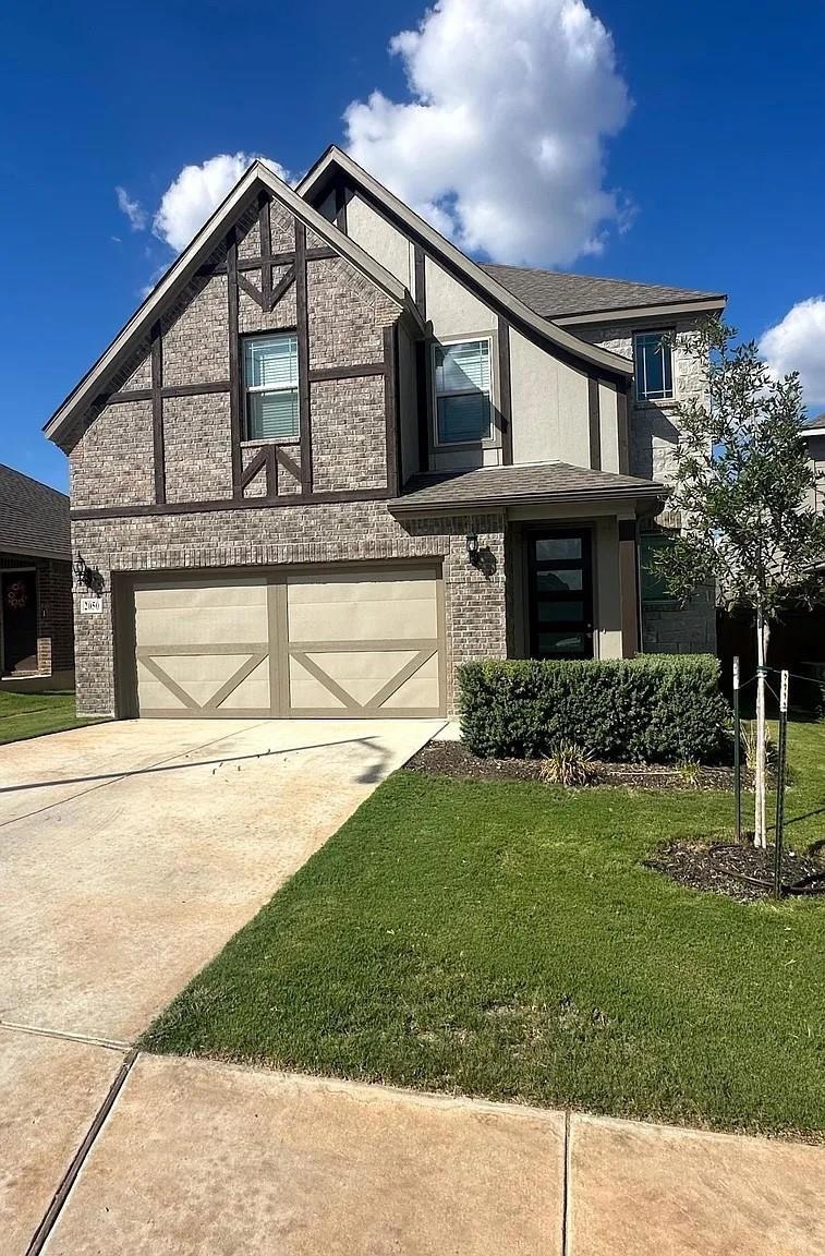 Tudor house with brick siding, a front yard, driv