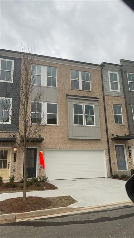 View of front facade featuring driveway, an attached garage, and stucco siding