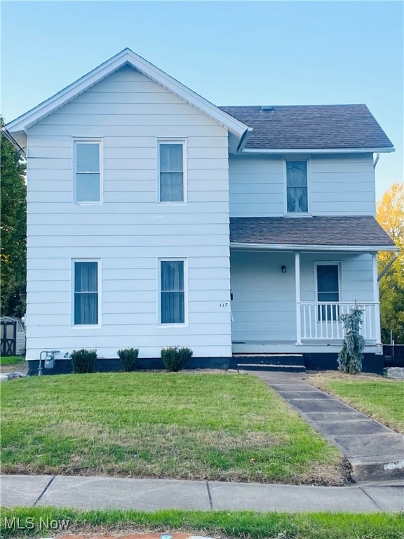 View of front of home with covered porch and a front yard