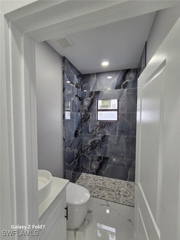 Bathroom with a marble finish shower, marble finish floors, vanity, and recessed lighting