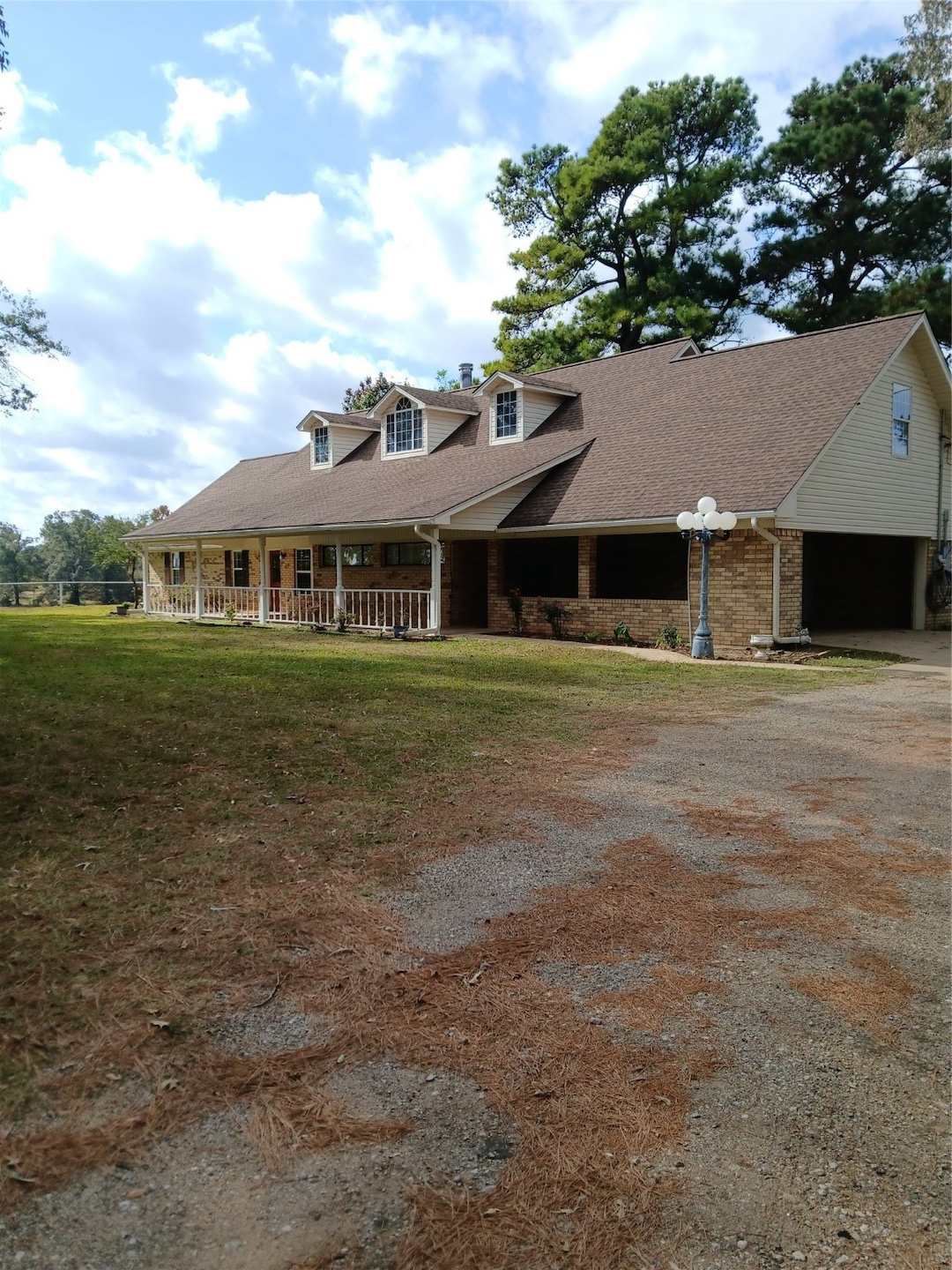 View of front of house featuring brick siding, a garage, driveway, a porch, and a shingled roof