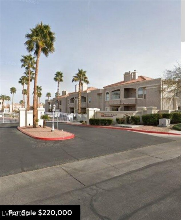 View of asphalt street featuring curbs and a gated entry