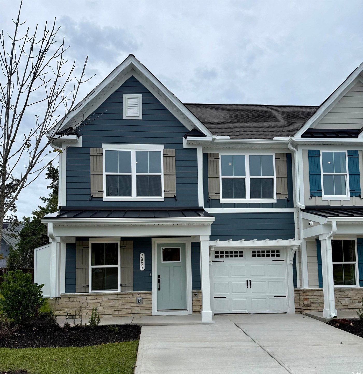 View of front facade with a standing seam roof, a metal roof, a residential view, a shingled roof, and stone siding