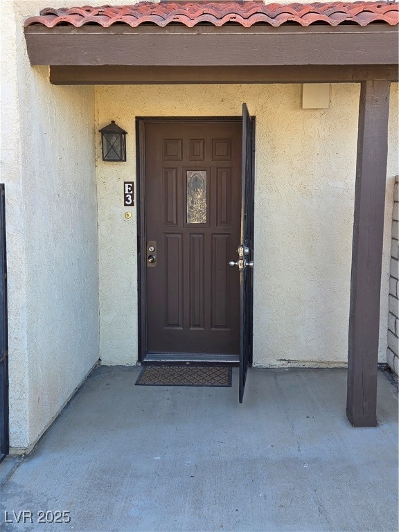 View of exterior entry with a tiled roof and stucc