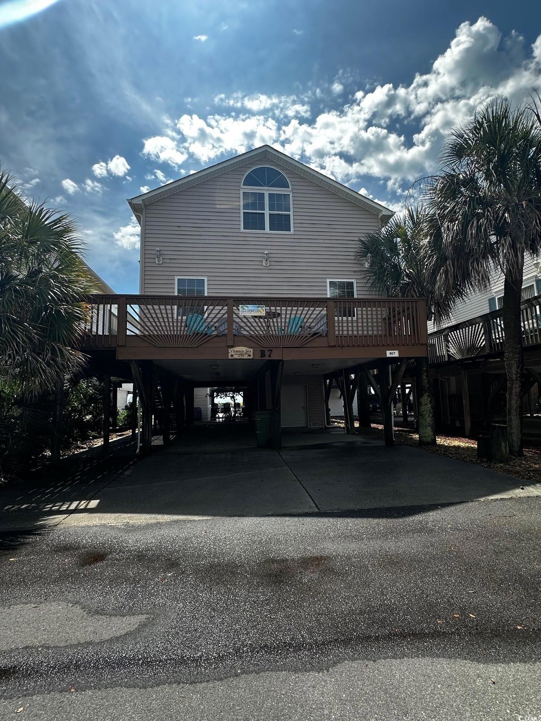 Back of house with a carport, driveway, and stairs