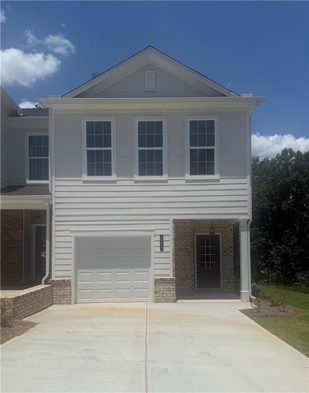 View of front facade featuring brick siding, a garage, and concrete driveway