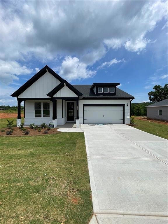 Modern inspired farmhouse with driveway, a front yard, board and batten siding, a garage, and roof with shingles