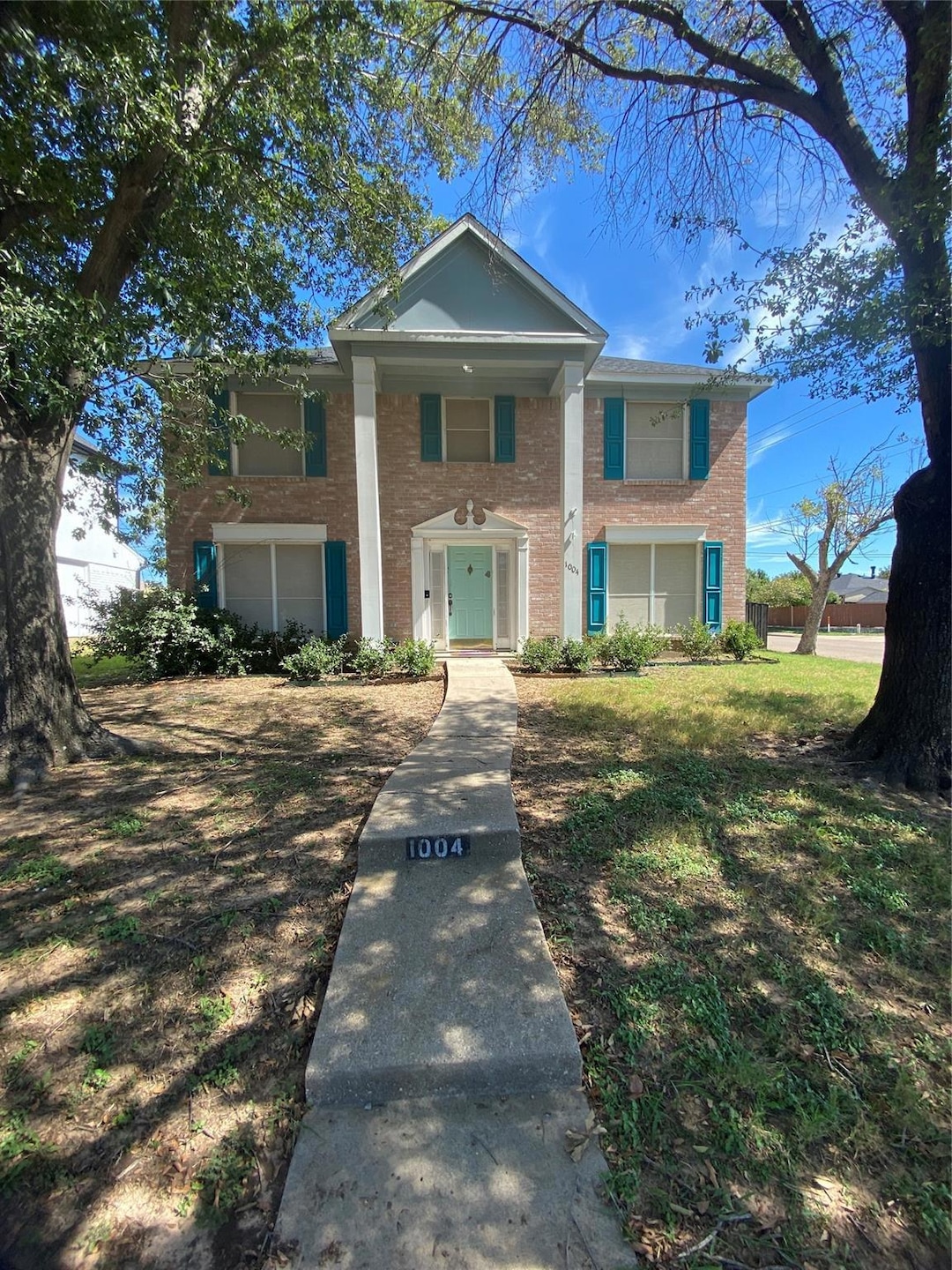 Neoclassical home featuring brick siding and a fro