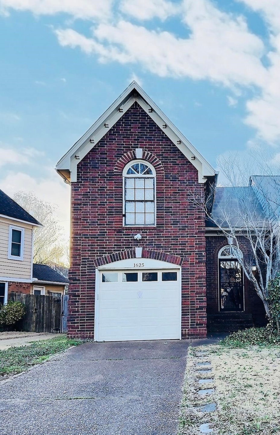 View of front of house with a garage, fence, brick