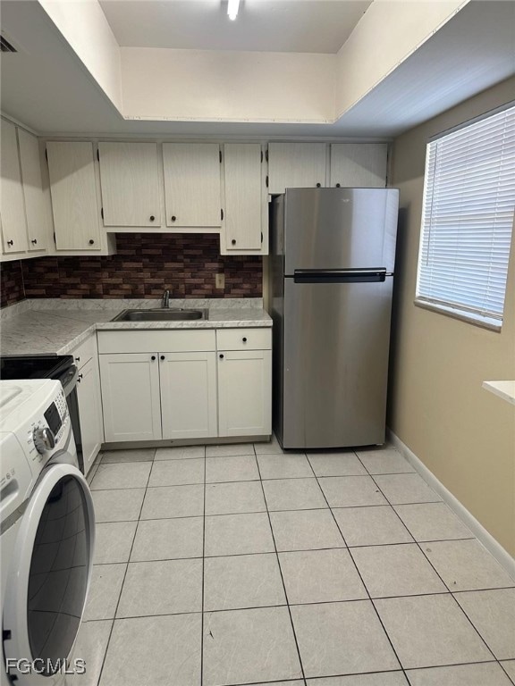 Kitchen featuring backsplash, light countertops, light tile patterned flooring, and washer / clothes dryer