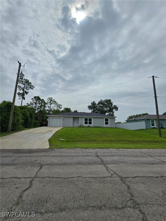 View of front of home featuring concrete driveway, a front lawn, and an attached garage
