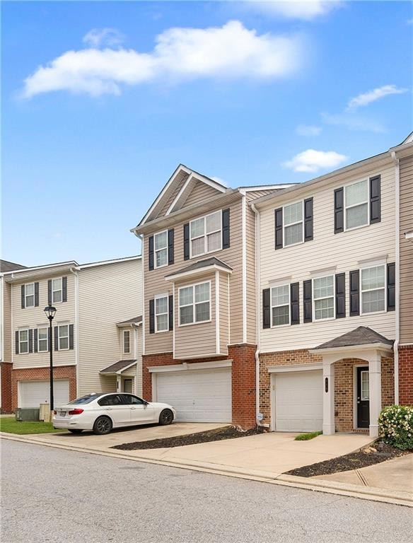 Multi unit property featuring brick siding, concrete driveway, and an attached garage