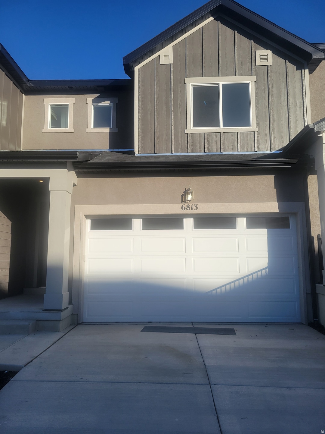 View of front of home with a garage, concrete driveway, and board and batten siding
