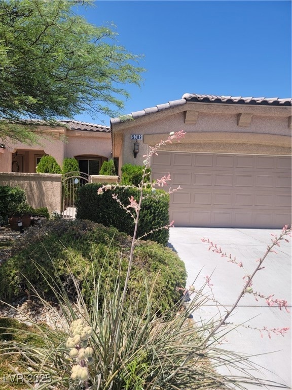 Pueblo-style home featuring a tiled roof, a garage