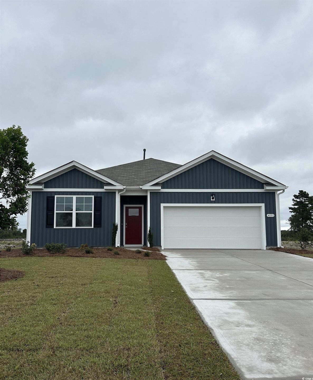 Single story home with a garage, a front lawn, driveway, and board and batten siding