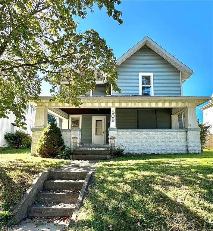 View of front of home with a front yard and a porc