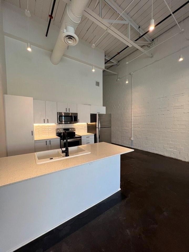 Kitchen featuring sink, a towering ceiling, applia