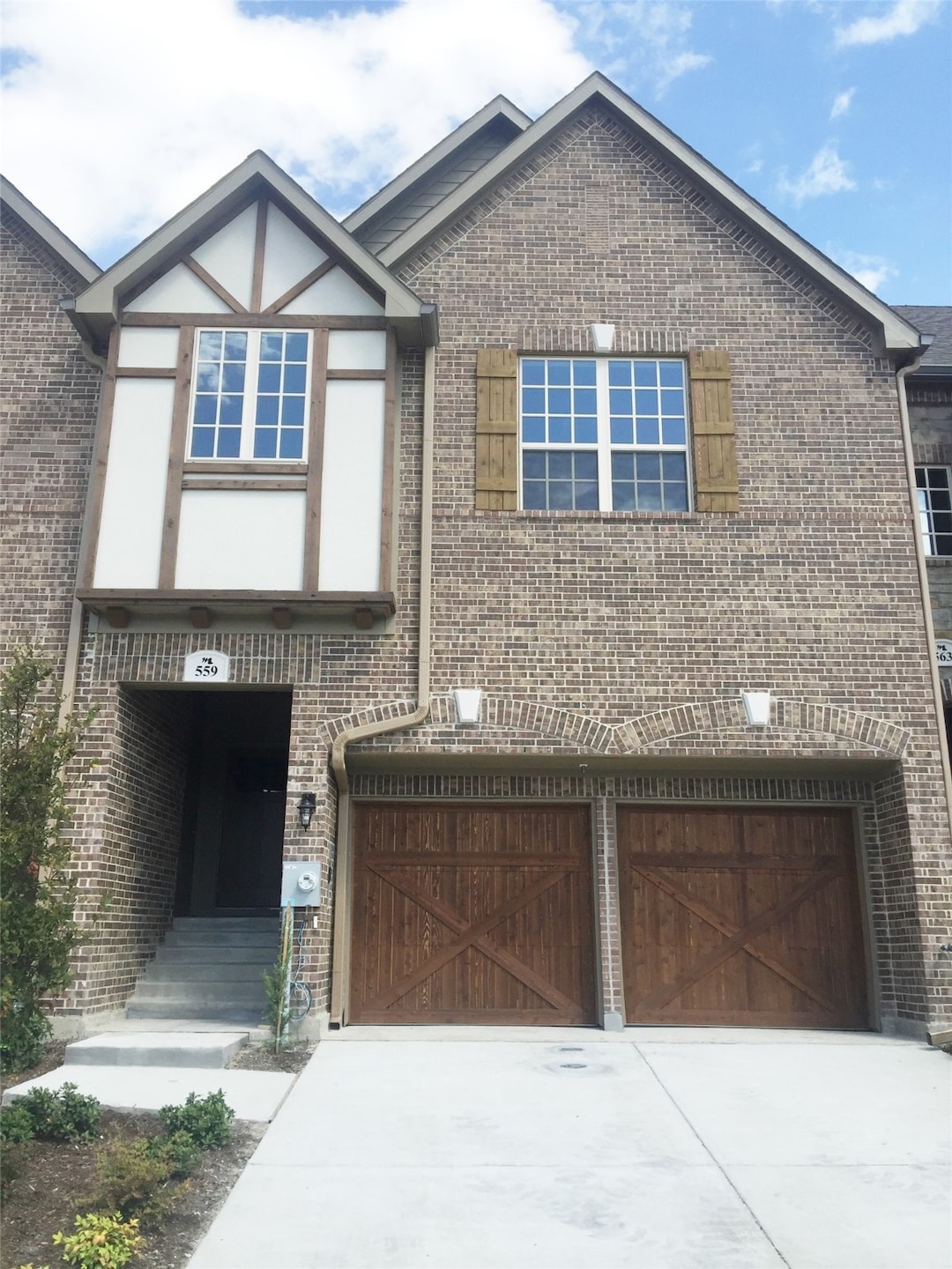 View of front of property with a garage, brick siding, and driveway