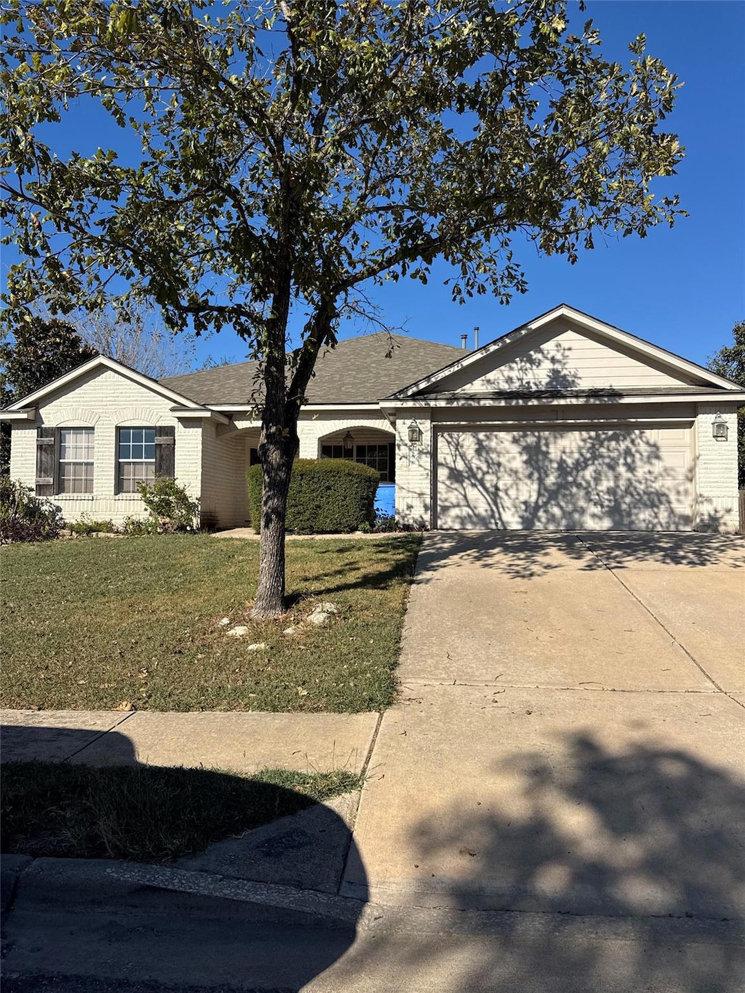 Ranch-style house with concrete driveway, a front yard, brick siding, and an attached garage