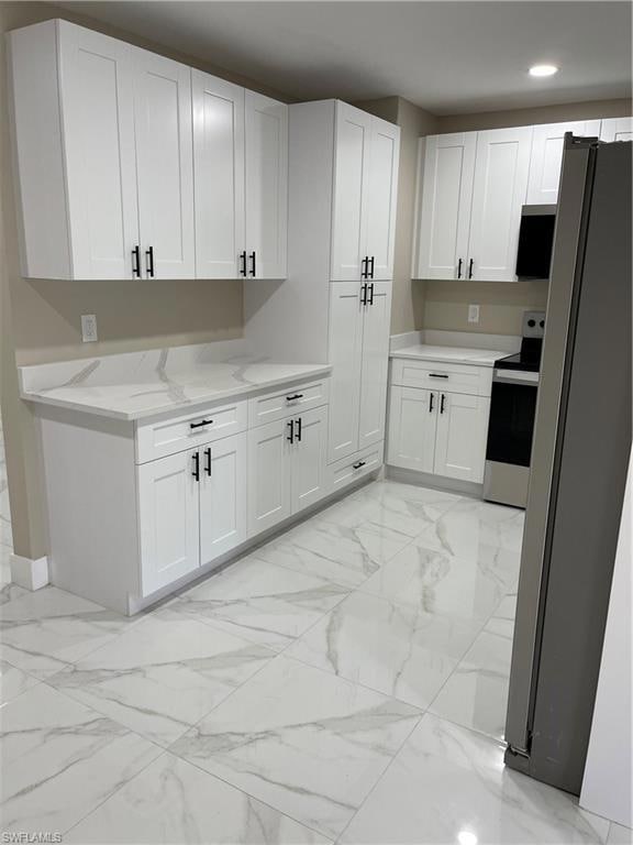 Kitchen featuring white cabinets, refrigerator, li