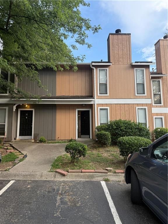 View of front of house with uncovered parking and a chimney