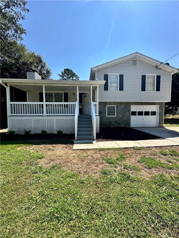 Tri-level home with covered porch, a chimney, a front yard, stone siding, and concrete driveway