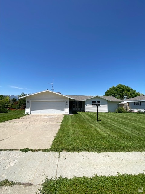 Single story home featuring an attached garage, a front lawn, and concrete driveway