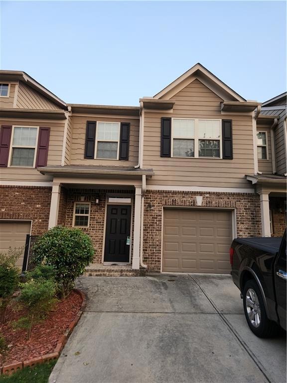 Multi unit property featuring concrete driveway, an attached garage, and brick siding