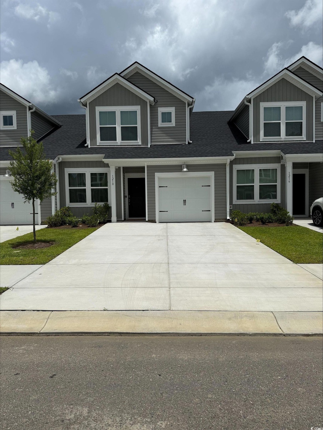 View of front of home with concrete driveway, board and batten siding, roof with shingles, and a garage