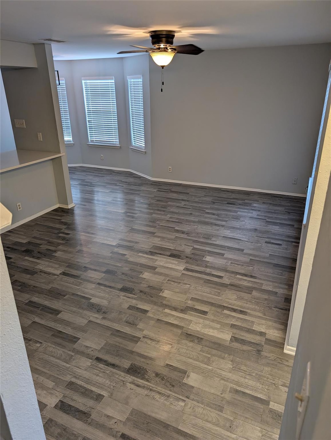 Unfurnished room with ceiling fan, dark wood-styl